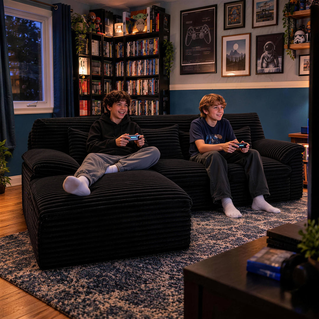 Two people playing video games on a black corduroy boneless sectional sofa