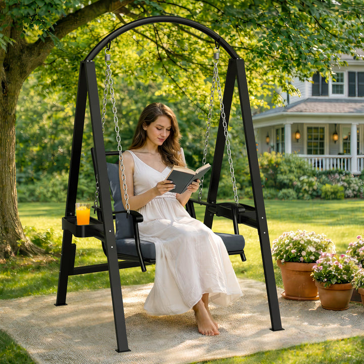 Woman reading on a Pamapic 1-seat porch swing chair in an outdoor garden setting